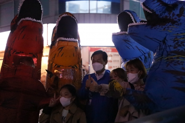 ▲나소열후보 선거캠프 공룡인형 복장 선거운동원 앞에서 유권자들이 기념 사진을 촬영하고 있다.