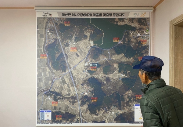 ▲한 주민이 군이 제작해 마을회관에 설치한 마을별 맞춤형 종합지도를 보고 있다.